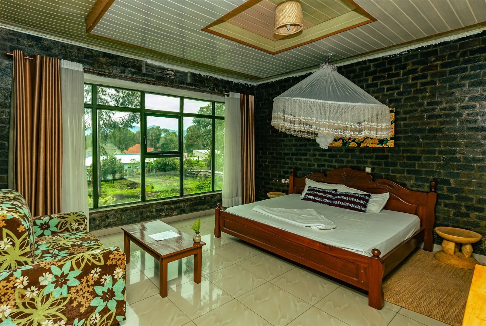 African-style double room with a patterned armchair, white netting and a wooden bed