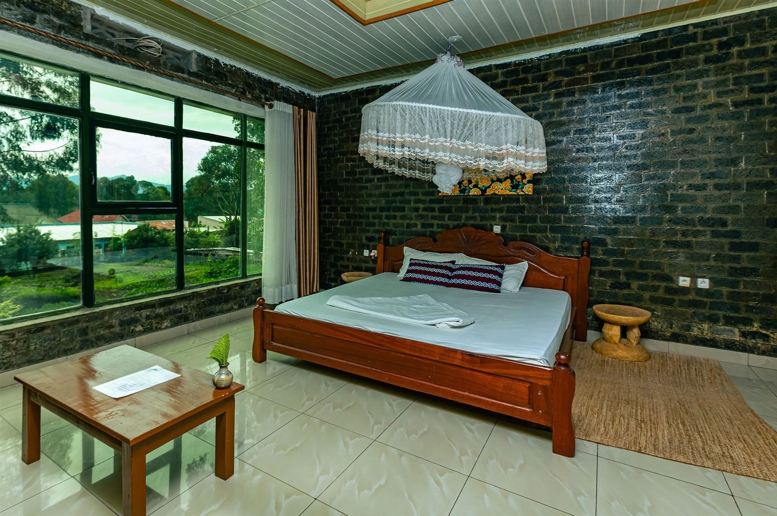 Double room with a wooden bed, a patterned armchair and garden light through the window