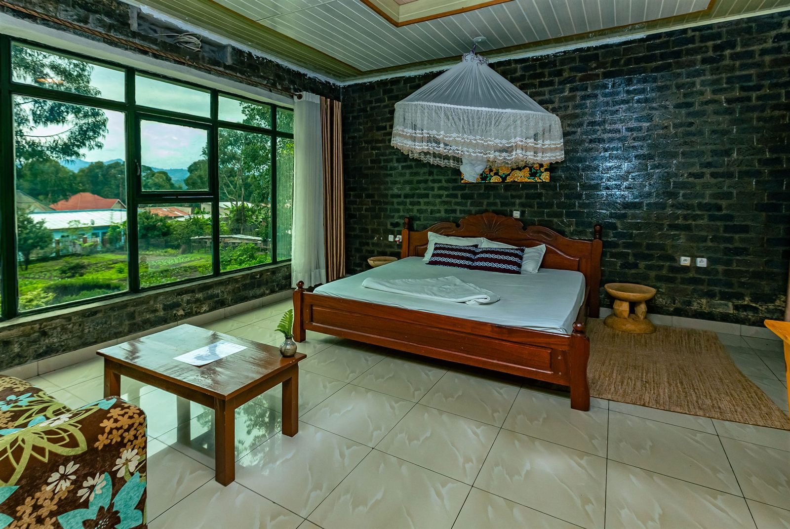 Double room with a wooden bed, brick feature wall and large windows onto the garden