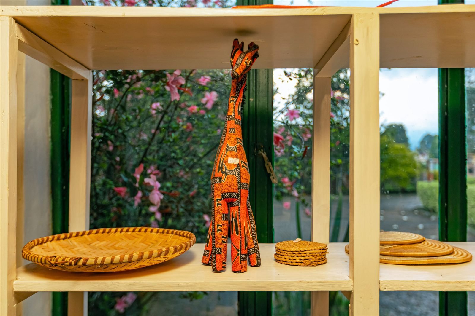 Carved giraffe and woven baskets on a wooden shelf in the souvenir shop