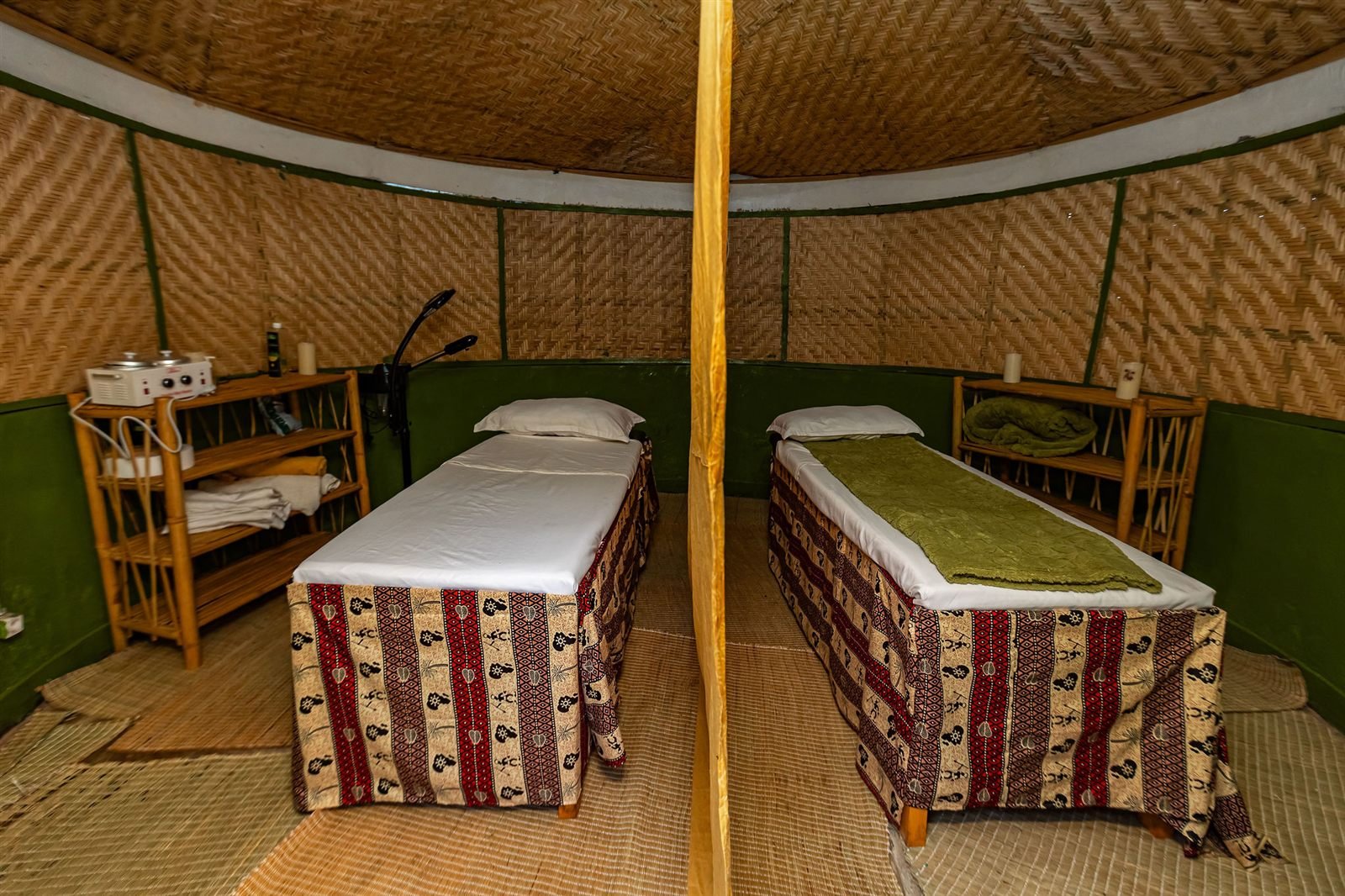 Two treatment beds with striped covers in a bamboo-walled room